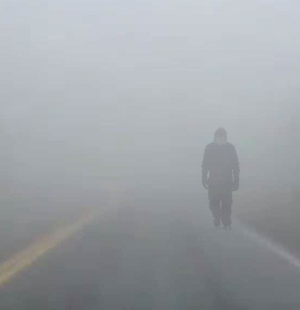 man nearly invisible walking in fog.